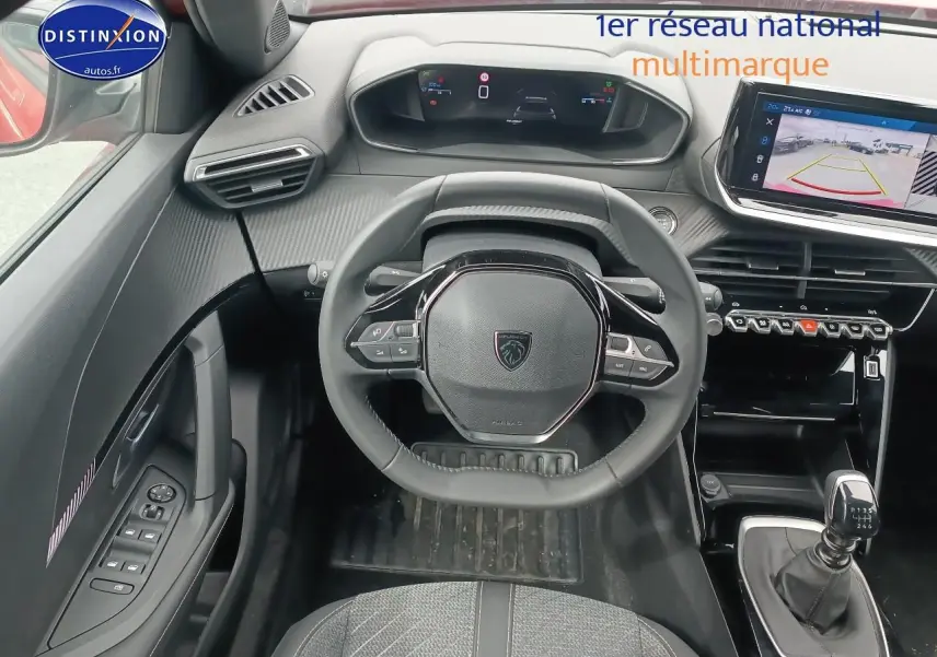 Vue intérieure avant centrée sur le volant compact et le tableau de bord numérique du Peugeot 2008 rouge Elixir.