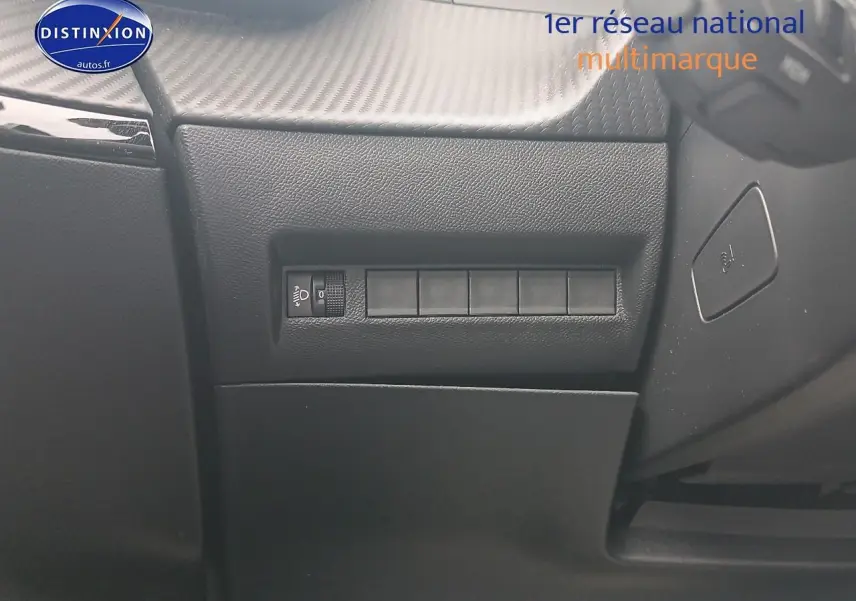 Détail intérieur du tableau de bord côté gauche avec commande de réglage des phares sur Peugeot 2008 Rouge Elixir.