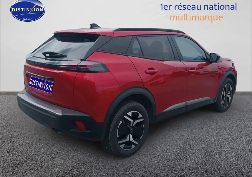 Vue 3/4 arrière droit d'un Peugeot 2008 rouge élixir avec jantes alu et vitres arrière teintées.