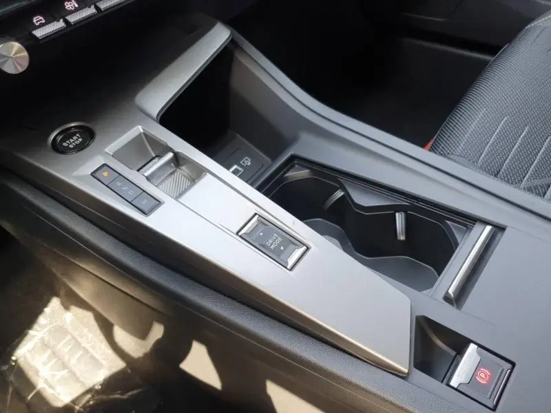 Vue rapprochée de la console centrale grise avec sélecteur de boîte auto et bouton start/stop du Peugeot 308 Hybrid 2026.