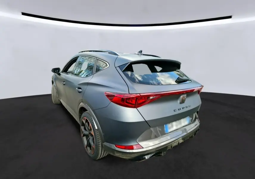 Vue 3/4 arrière droite d’un CUPRA Formentor gris foncé mat, avec feux arrière allongés et jantes noires aux accents cuivrés.