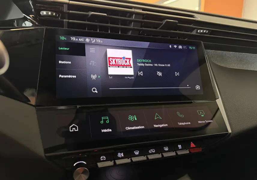 Vue rapprochée de l’écran tactile central du tableau de bord de la Peugeot 308 Hybrid 145 Allure avec interface multimédia et climatisation.