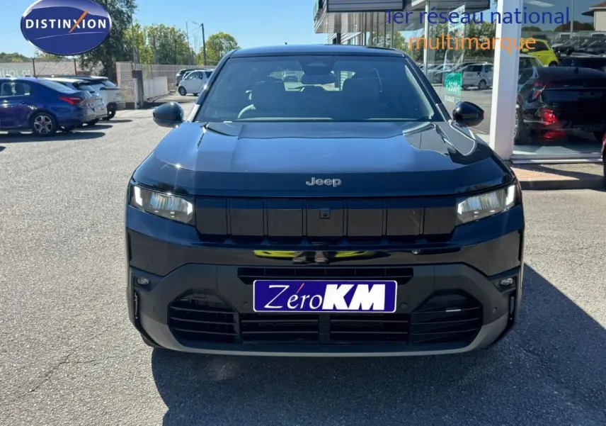 Vue frontale d'un Jeep Compass 2026 couleur Vulcano avec calandre noire et phares LED allumés.