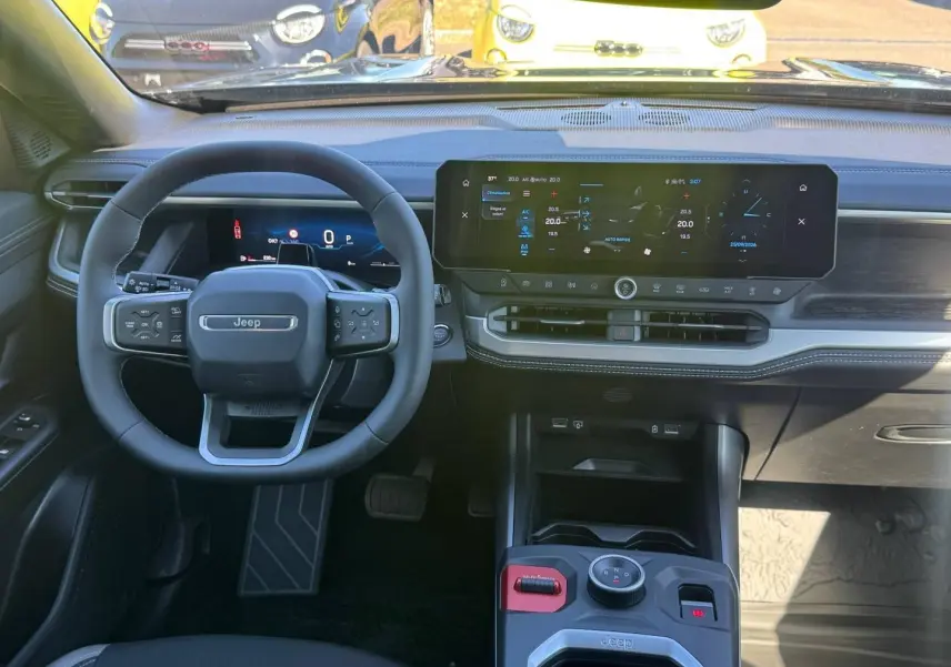 Vue intérieure frontale du tableau de bord et volant Jeep Compass 2026 avec écran tactile large et commandes au volant.