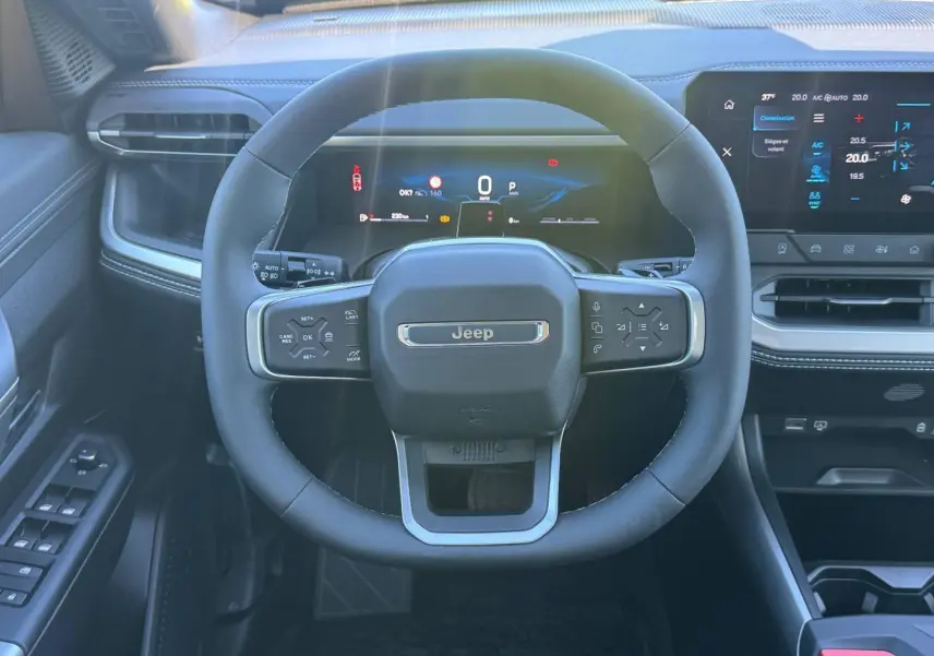 Vue intérieure centrée sur le volant Jeep du Compass 2026, avec tableau de bord numérique et écran tactile à droite.