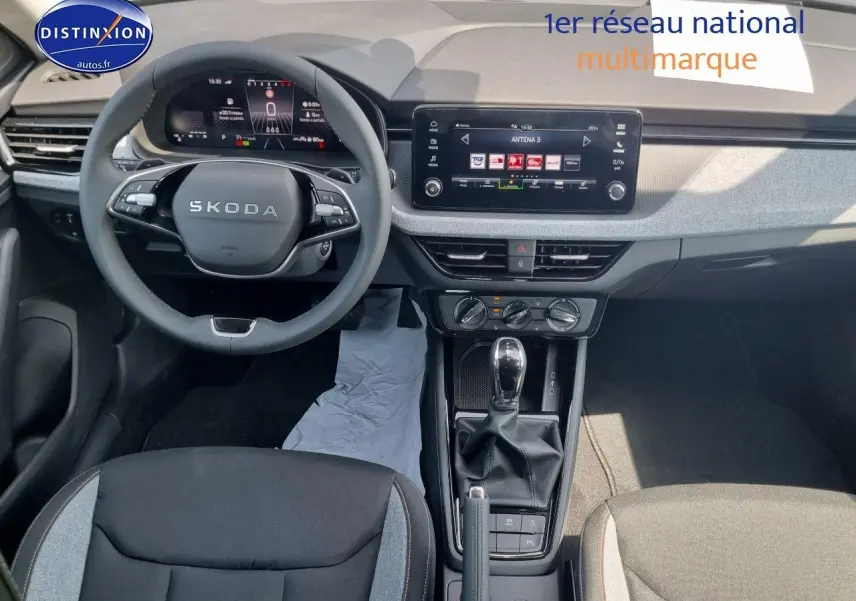 Intérieur du Skoda Kamiq 2025 en vue plongeante, tableau de bord moderne avec écran tactile et volant multifonction noir.