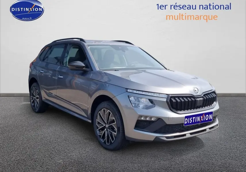 Vue 3/4 avant d'un Skoda Kamiq gris graphite avec barres de toit noires et jantes alliage distinctives.