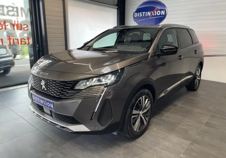 Peugeot 5008 gris platinium vue 3/4 avant droit en intérieur avec calandre chromée et jantes bi-ton 18 pouces.