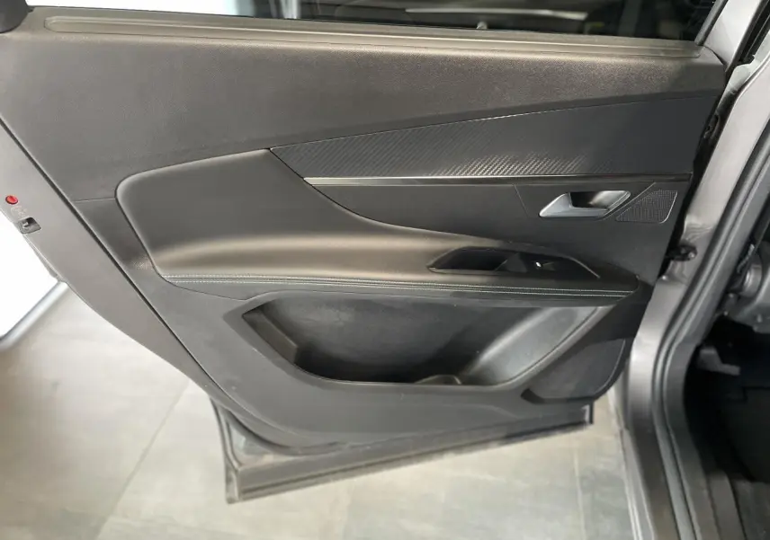 Porte arrière gauche ouverte du Peugeot 5008 gris platinium, avec garniture noire et insert effet carbone.