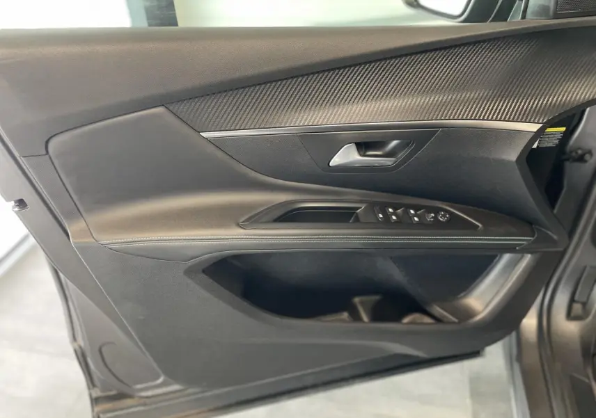 Panneau de porte avant gauche noir avec insert carbone et commandes électriques sur Peugeot 5008 gris platinium 2024