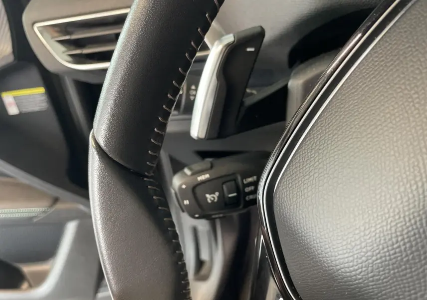Gros plan sur le volant en cuir noir Mistral du Peugeot 5008 2024, avec commandes intégrées et palettes au volant.