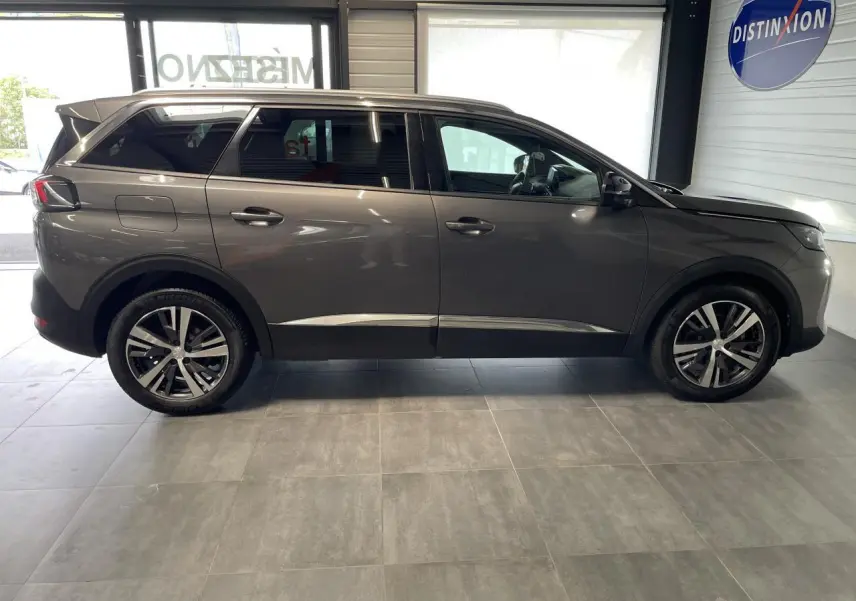 Profil droit du Peugeot 5008 gris platinium 2024 avec jantes alliage bi-ton et vitres arrière surteintées.
