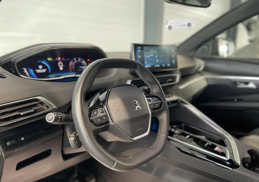 Intérieur du Peugeot 5008 2024 vu côté conducteur, volant compact cuir noir et tableau de bord numérique.