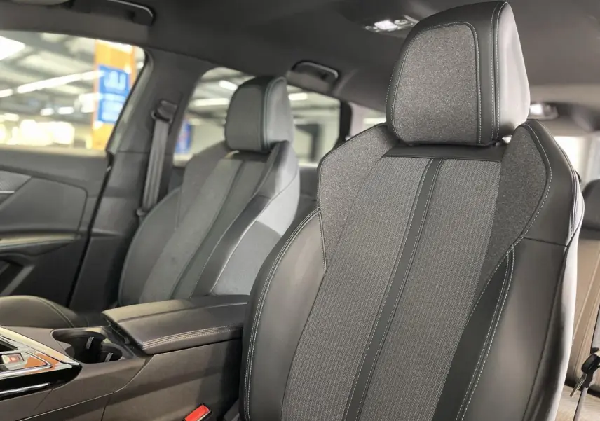 Gros plan sur les sièges avant gris TEP et tissu du Peugeot 5008 2024 avec accoudoir central et coutures contrastées.