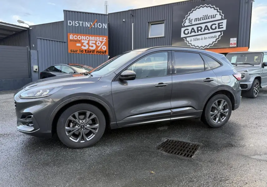 Ford Kuga gris métallisé vu de profil côté gauche, avec jantes alliage 18 pouces et vitres arrière surteintées.