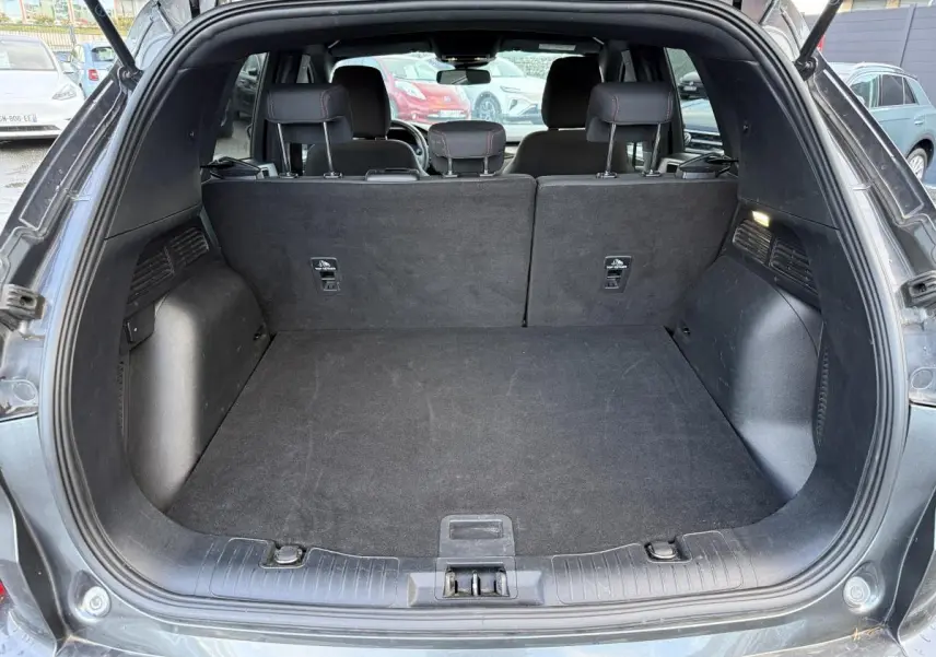 Coffre ouvert d'un Ford Kuga gris 2022, vue arrière montrant l'espace de chargement et la banquette arrière noire.