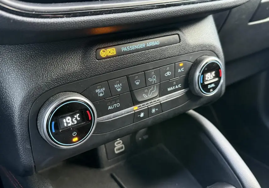 Gros plan sur la console centrale noire du Ford Kuga 2022 avec commandes de climatisation automatique bi-zone.