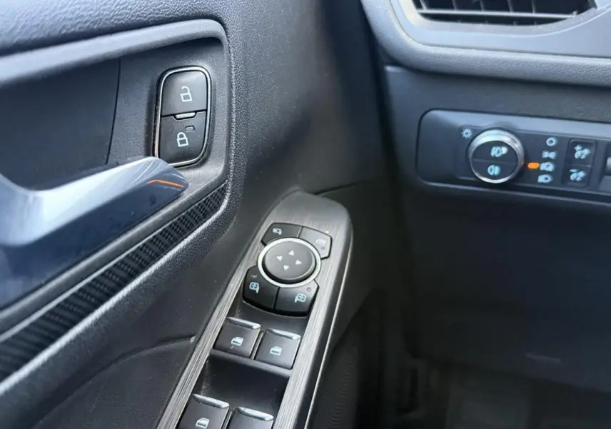 Détail des commandes de porte côté conducteur du Ford Kuga gris 2022, avec boutons de verrouillage et réglage des rétroviseurs.