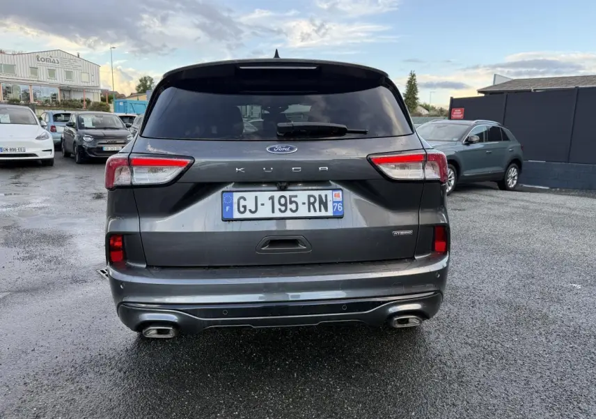 Vue arrière d'un Ford Kuga gris métallisé 2022 avec double sortie d'échappement et badges Hybrid et ST-Line.