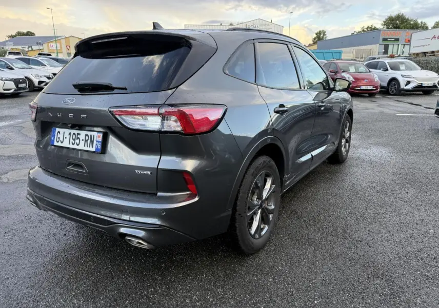 Vue 3/4 arrière droite d'un Ford Kuga gris métallisé avec vitres surteintées et double sortie d'échappement ST-Line.