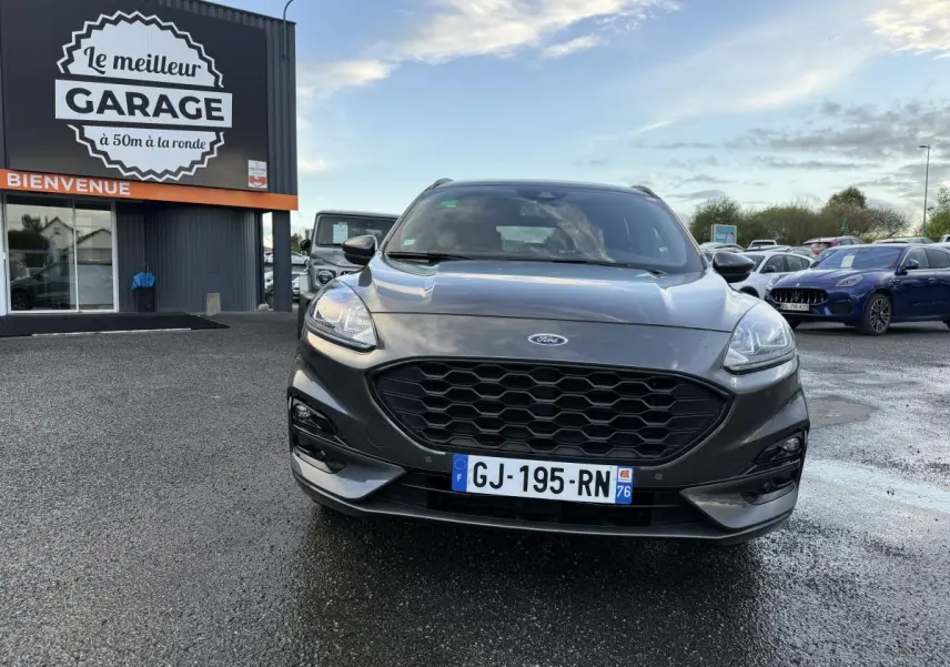 Vue frontale d'un Ford Kuga gris métallisé avec calandre noire et double sortie d'échappement ST-Line visible.