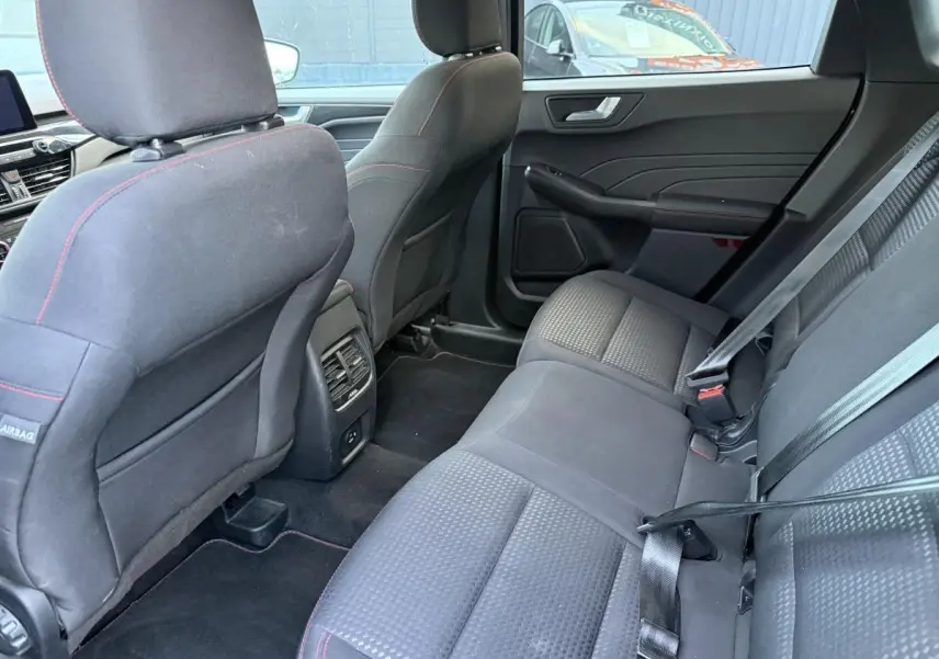 Vue intérieure arrière côté droit du Ford Kuga 2022 gris, sièges tissu noir avec surpiqûres rouges et ceintures de sécurité.