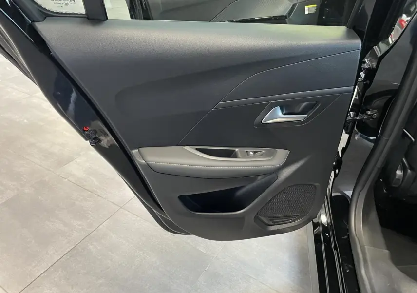 Vue rapprochée de la porte arrière gauche noire du Peugeot 208 2025 avec garniture grise et haut-parleur intégré.