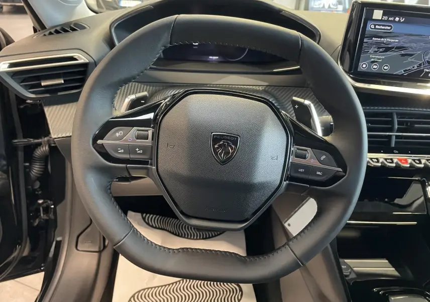 Volant cuir noir de Peugeot 208 2025 en vue frontale avec commandes intégrées et tableau de bord numérique.