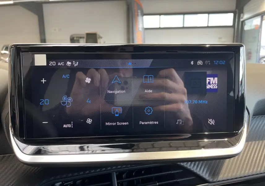 Écran tactile central du tableau de bord de la Peugeot 208 noir, affichant les options de navigation et climatisation.