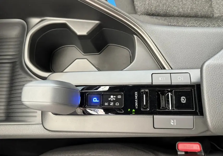 Vue rapprochée de la console centrale du Toyota C-HR blanc 2024, montrant le levier de vitesses automatique et les boutons de contrôle.