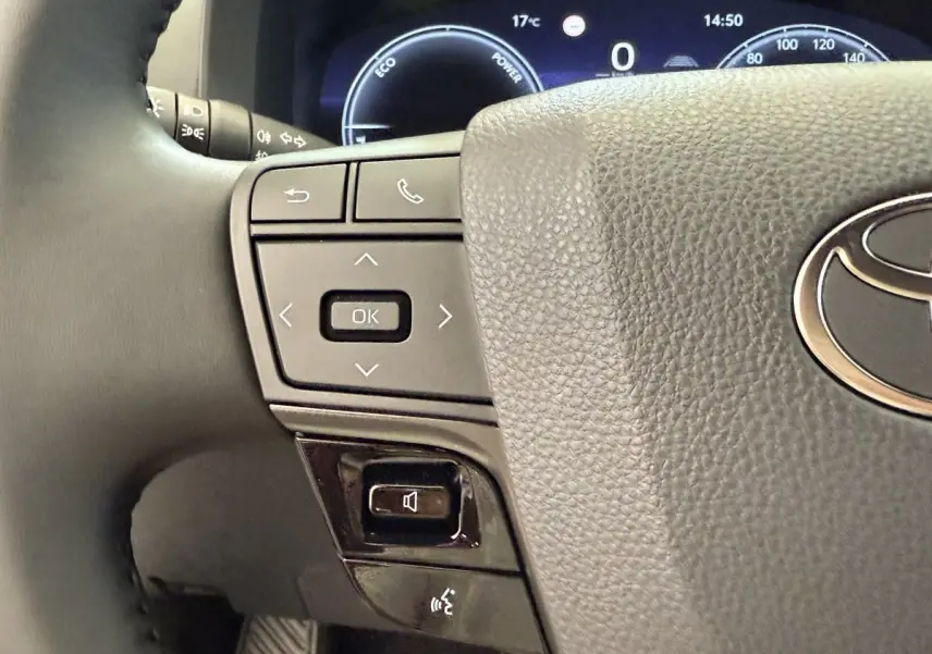 Gros plan sur le volant cuir noir du Toyota C-HR 1.8 Hybride 140 Dynamic avec commandes multifonctions et combiné d'instruments digital.