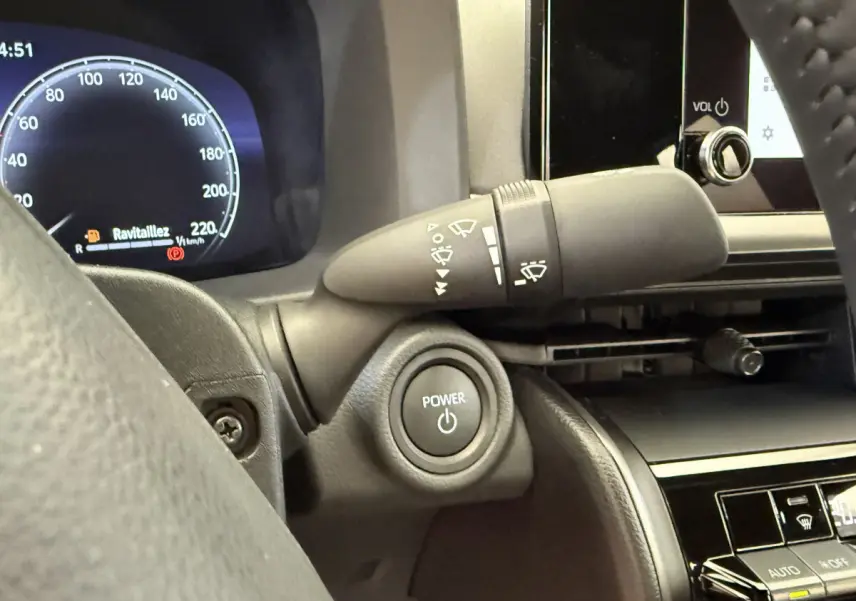 Gros plan intérieur sur le bouton Power et le combiné d'instruments numérique du Toyota C-HR 1.8 Hybride 2024.