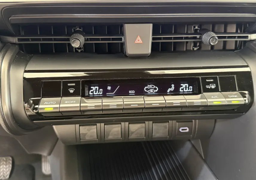 Gros plan sur la console centrale du Toyota C-HR blanc 2024, affichant la climatisation digitale à deux zones.