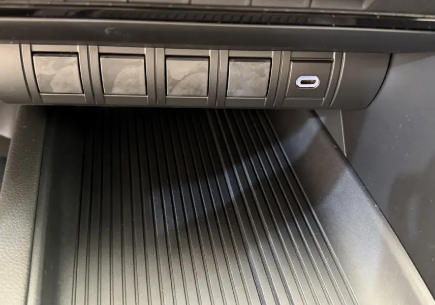 Gros plan sur la prise USB-C et les boutons au-dessus du rangement central du Toyota C-HR blanc 2024.