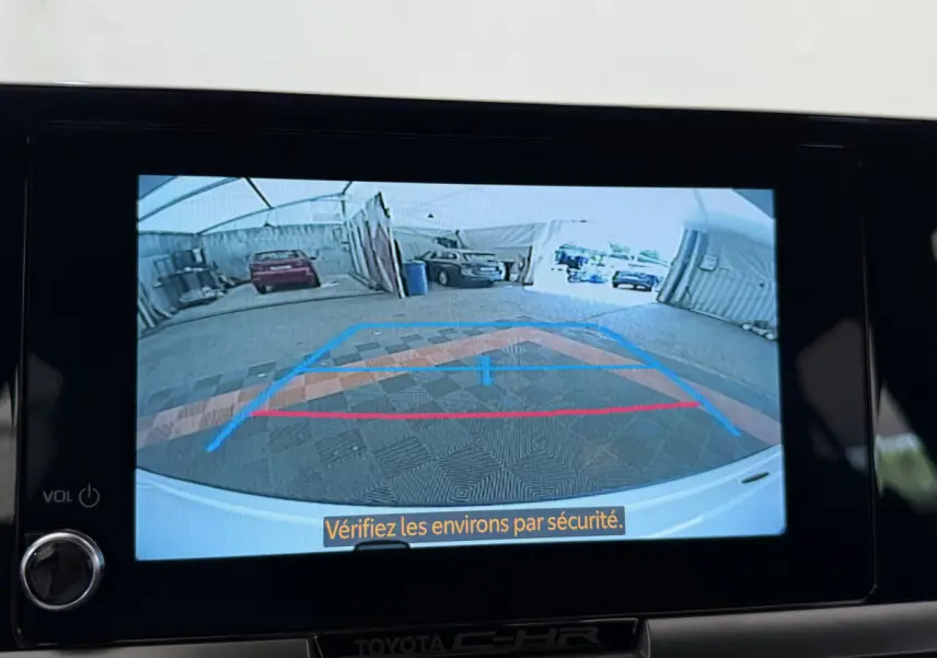 Vue caméra de recul du Toyota C-HR blanc 2024, affichée sur l'écran central avec guidage de trajectoire coloré.