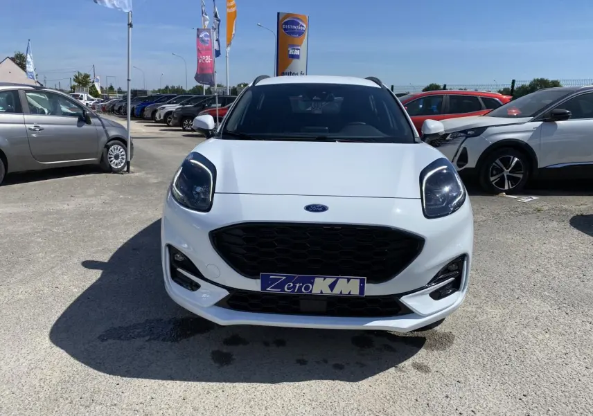 Vue avant d'un Ford Puma blanc glacier avec calandre noire et barres de toit noires sur parking extérieur.