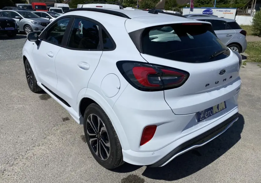 Vue 3/4 arrière droite d'une Ford Puma blanche Glacier avec jantes noires et barres de toit noires.