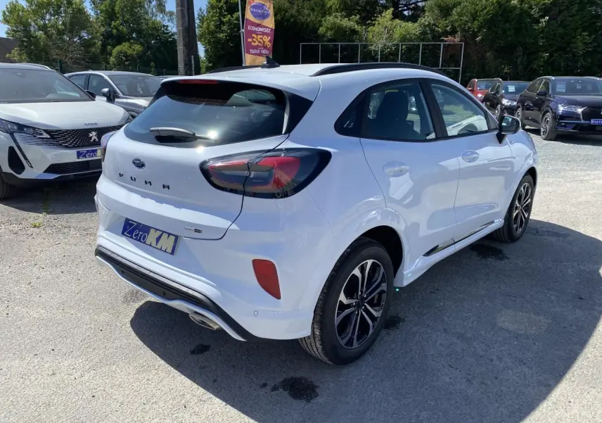 Vue 3/4 arrière droite d’un Ford Puma blanc glacier avec barres de toit noires et jantes alliage 17 pouces finition Black Machined.
