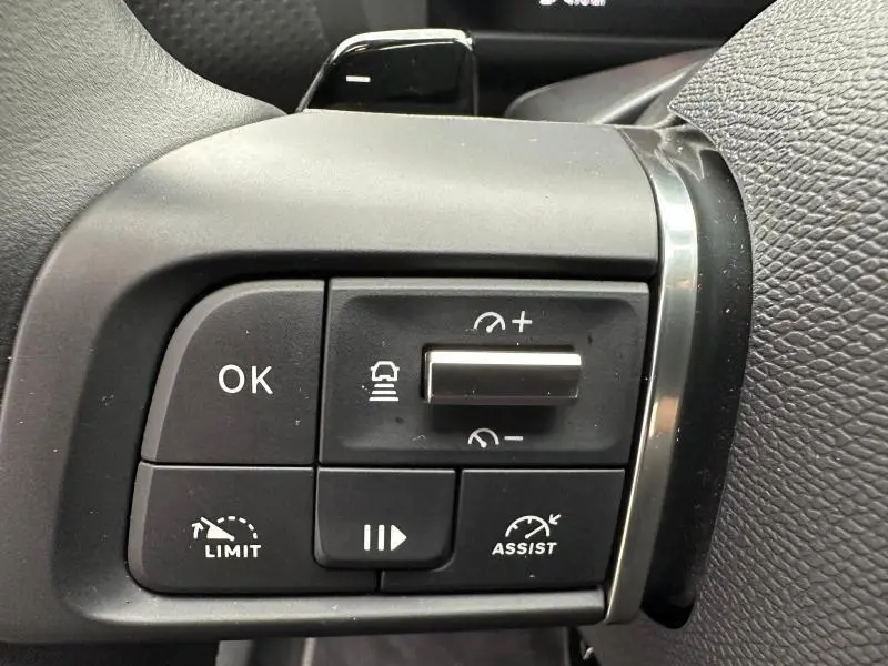 Gros plan sur les commandes au volant gauche du Citroën C4 X 1.2 Hybride 2025 en Gris Mercury, boutons de régulateur et assistances visibles.