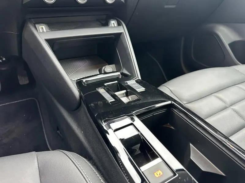 Vue rapprochée de la console centrale noire brillante et siège avant gris du Citroën C4 X hybride 2025.