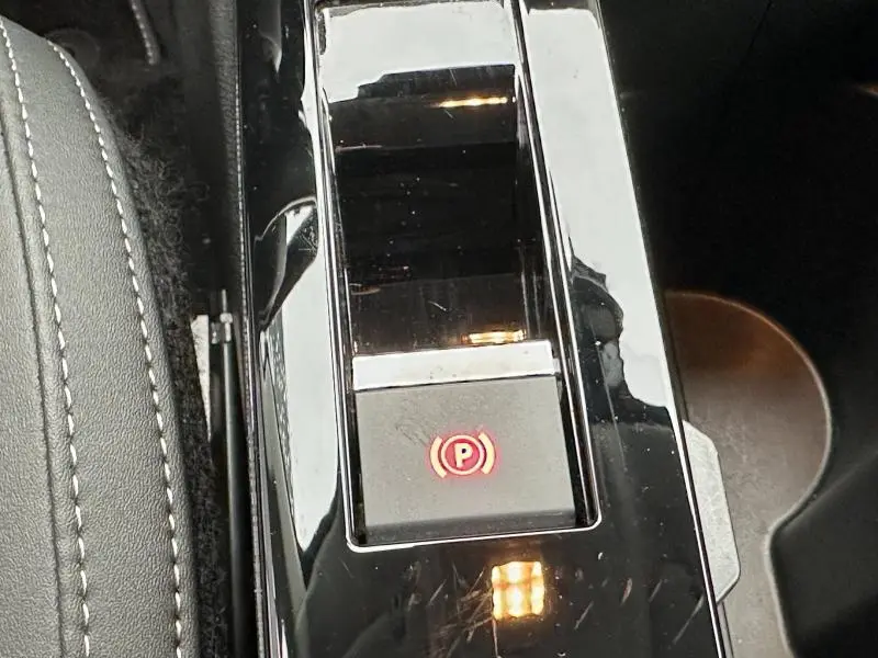 Gros plan sur la console centrale du Citroën C4 X 2025 avec bouton de frein à main électronique éclairé en rouge.