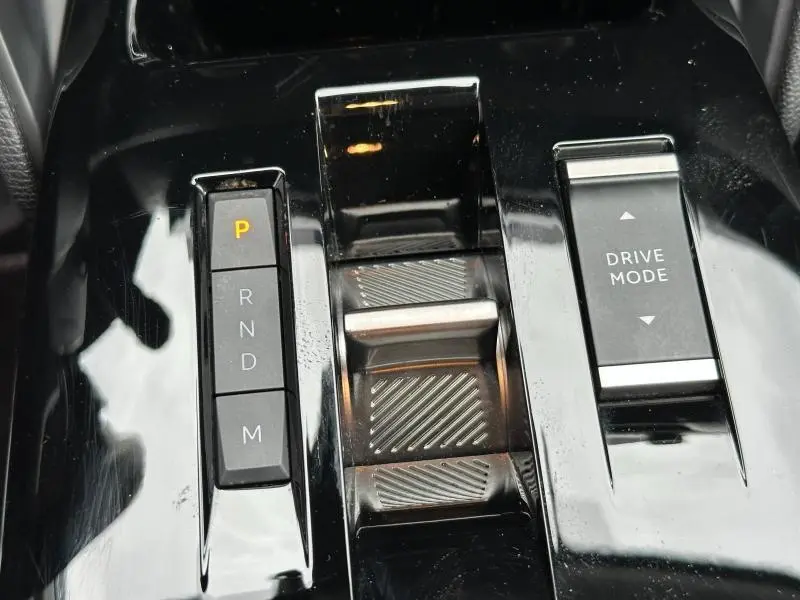Gros plan sur la console centrale noire brillante du Citroën C4 X 2025, avec sélecteur de boîte auto et bouton Drive Mode.