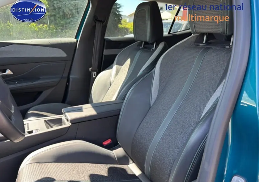 Vue intérieure côté droit des sièges avant en tissu et cuir du Peugeot 408 Hybrid 145 allure bleu 2025 avec accoudoir central.