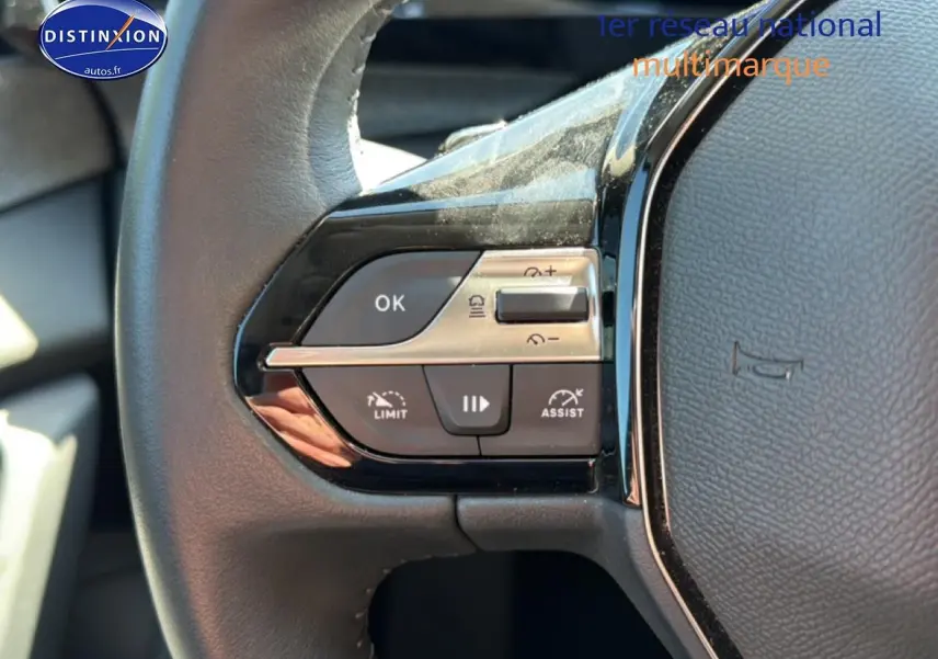 Gros plan sur les commandes multifonctions à gauche du volant cuir noir du Peugeot 408 Hybrid 145 allure bleu 2025.