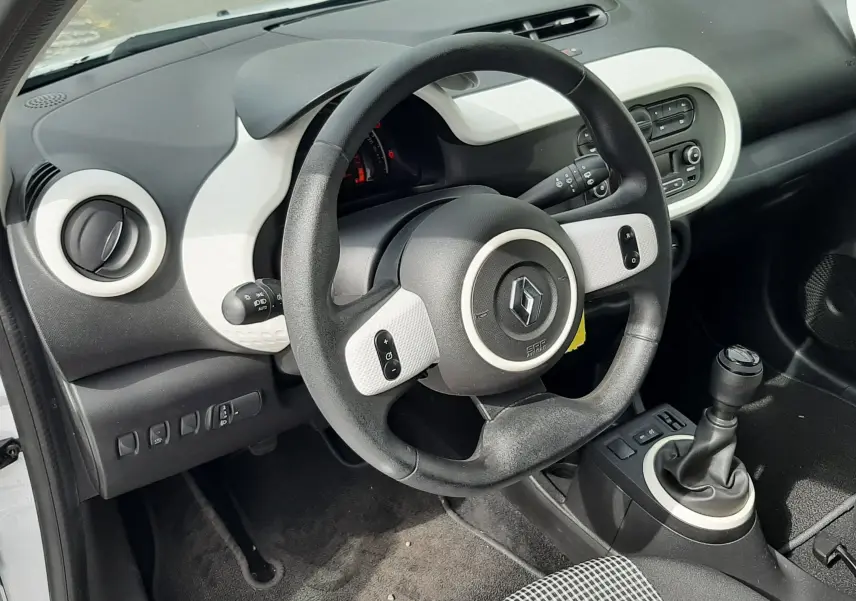 Gros plan sur les commandes de lève-vitres côté conducteur de la Renault Twingo III blanc cristal, finition tissu gris-noir.