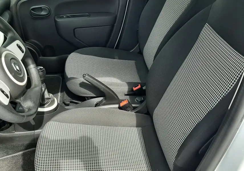 Vue intérieure côté conducteur de la Renault Twingo III blanc cristal, volant multifonction et levier de vitesse manuel visibles.