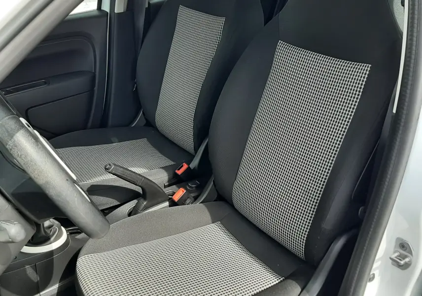 Vue intérieure côté gauche de la Renault Twingo III Life 2021, sièges tissu gris noir avec motifs à carreaux.