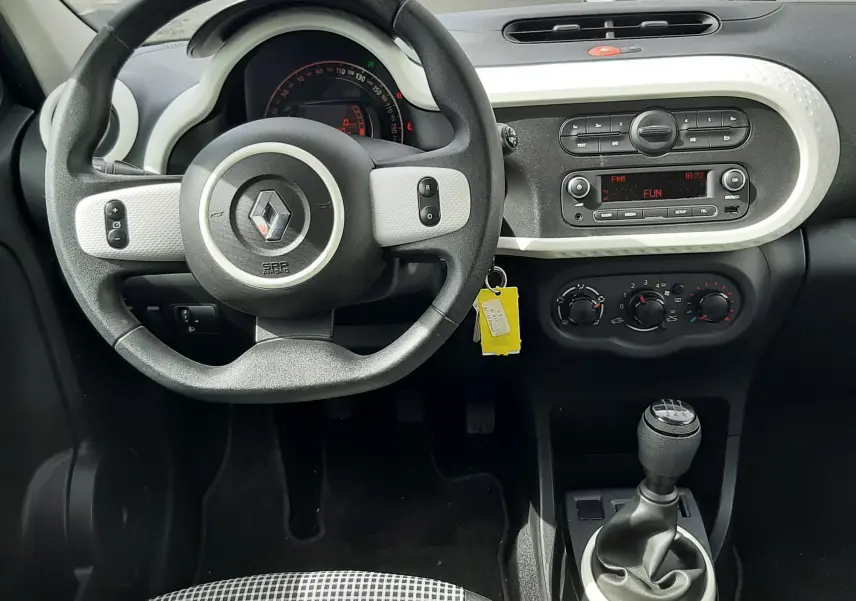 Vue intérieure côté droit des sièges arrière en tissu gris noir de la Renault Twingo III blanc cristal, avec ceintures de sécurité visibles.