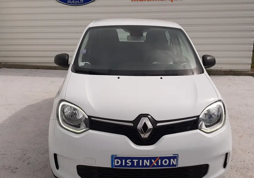 Vue rapprochée du pare-brise d’une Renault Twingo III blanc cristal avec affichage du prix et mensualité en jaune.