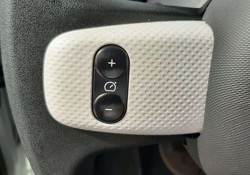 Panneau de commandes intérieures noires avec interrupteurs et molette de réglage des phares dans une Renault Twingo III blanc cristal.